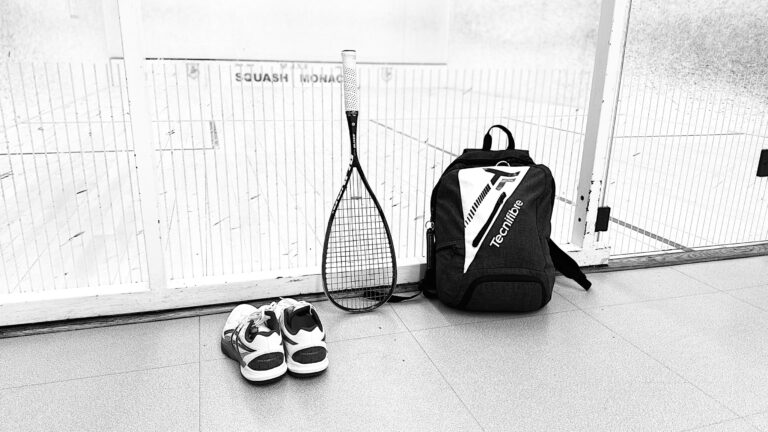 Raquette, chaussures et sac de squash devant un court du club de squash de Monaco